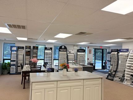 Bright office with sample racks, tables, and a central island under fluorescent lights