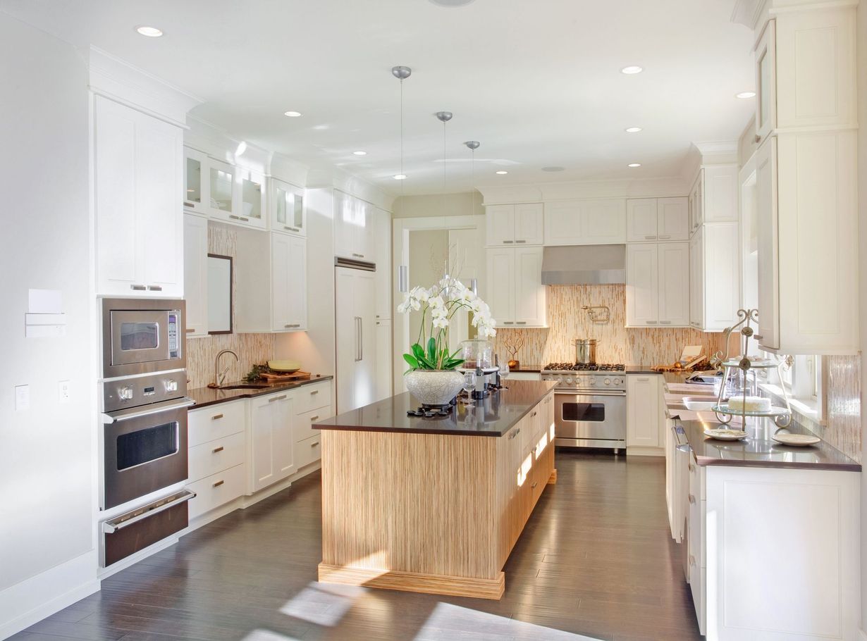 Bright modern kitchen with white cabinets, dark island, and stainless steel appliances