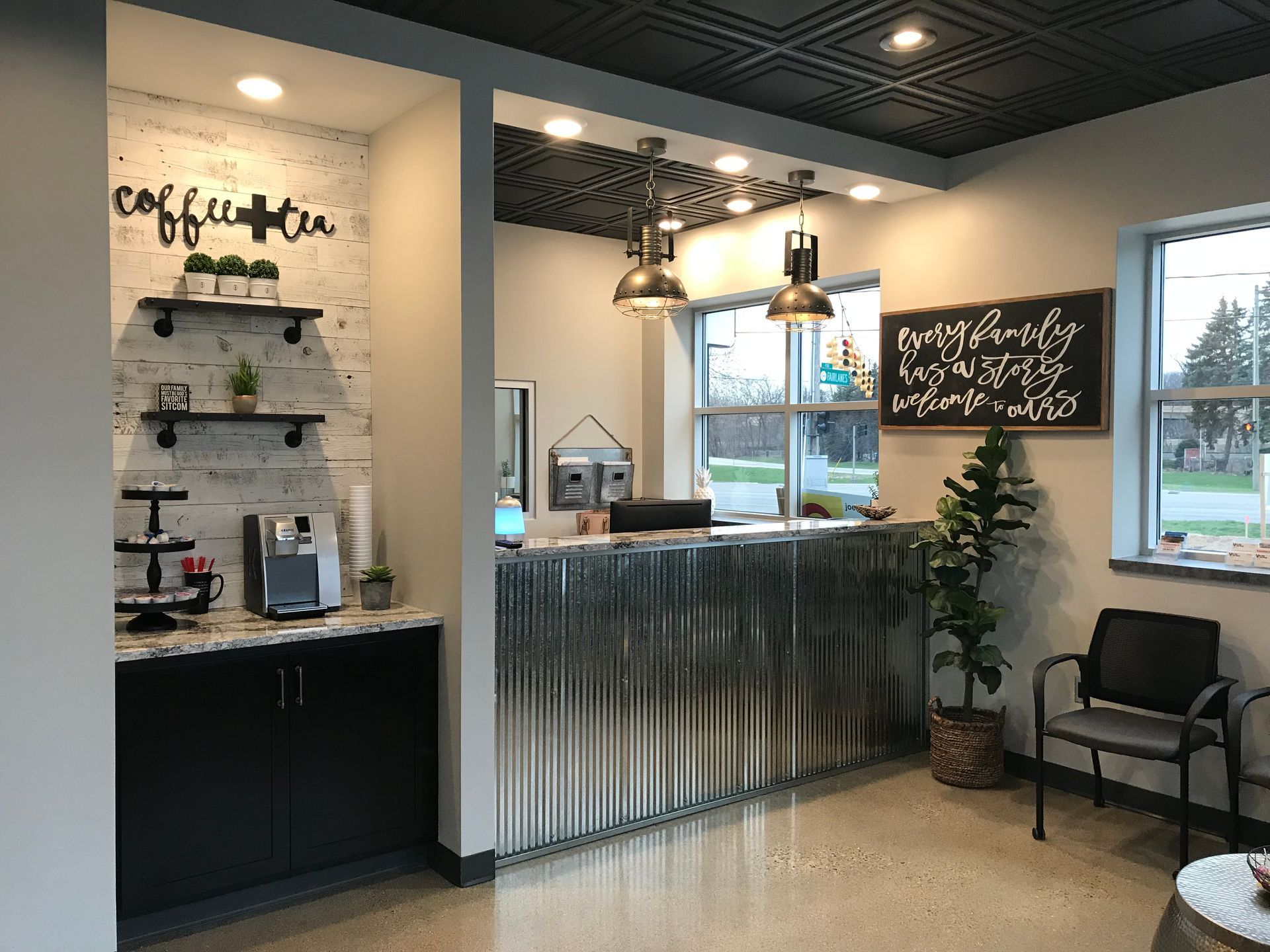Coffee shop counter with corrugated metal front, chalkboard menu, and seating area by windows.