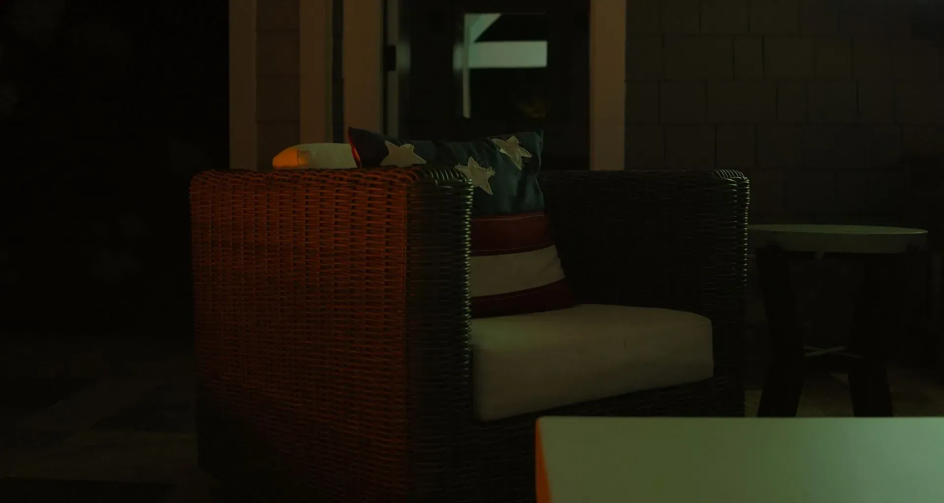 A chair with an American flag pillow on a dark patio
