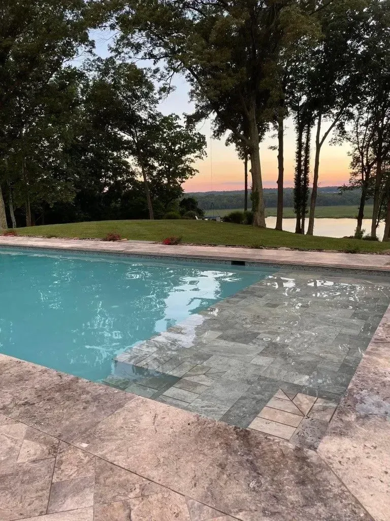 a large swimming pool surrounded by trees and a lake