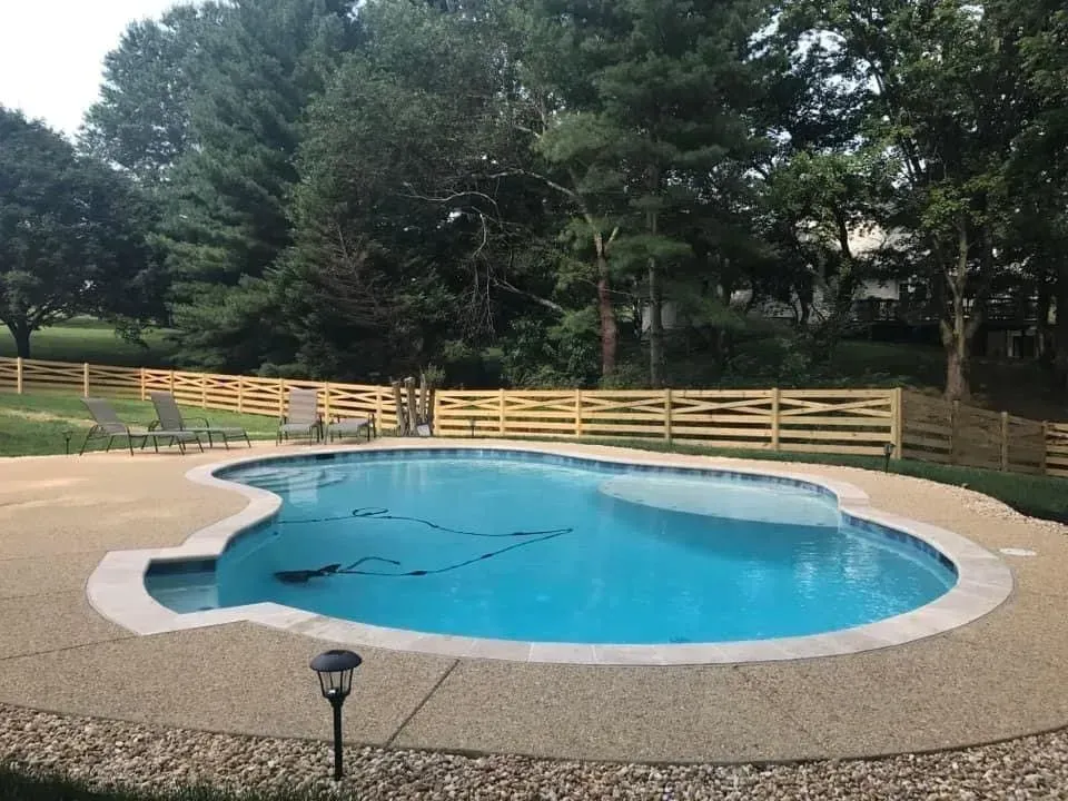 a large swimming pool with a wooden fence around it