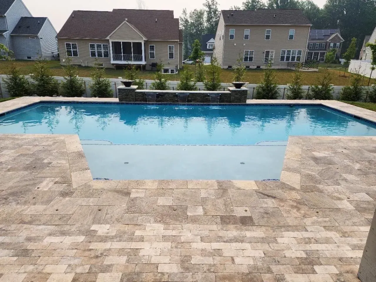a large swimming pool with a house in the background