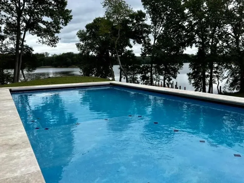 a large swimming pool surrounded by trees and a lake