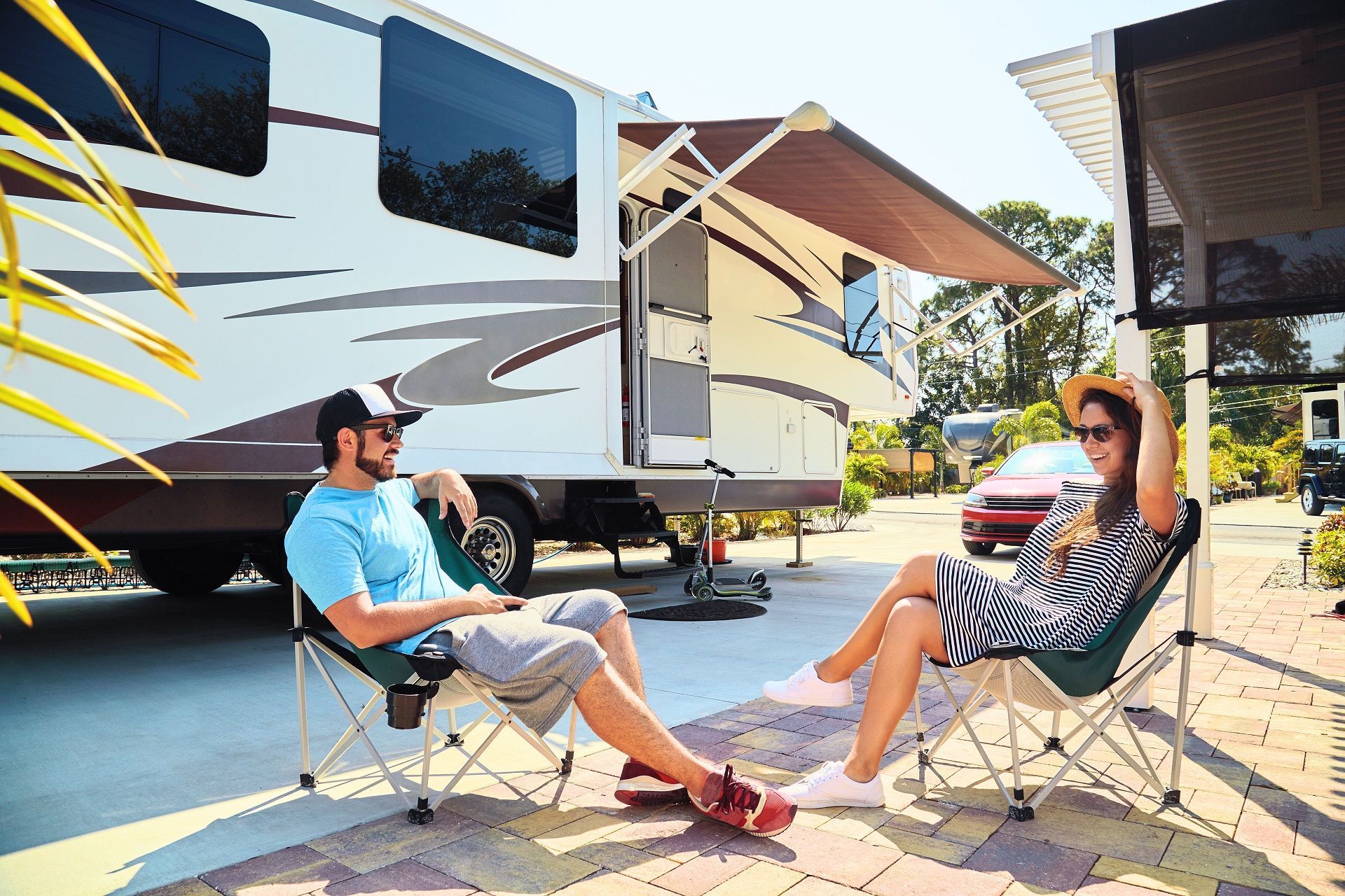 a man and a woman are sitting in chairs in front of a rv .