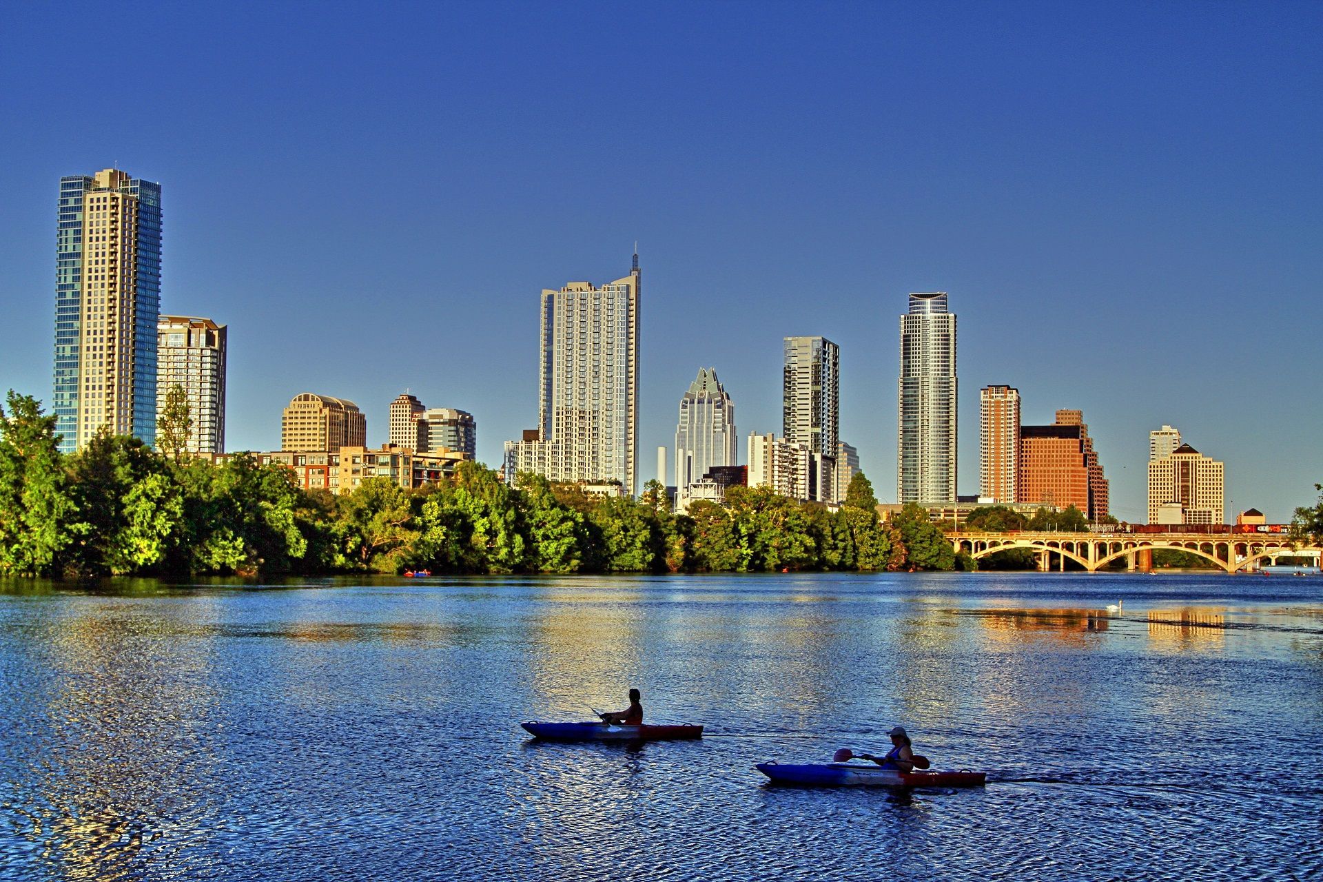 two people in kayaks on a lake with a city skyline in the background