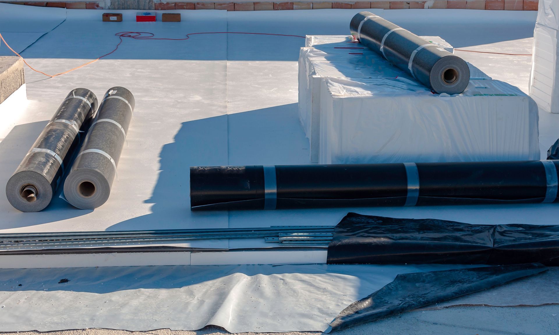 Three rolls of roofing material are sitting on top of a roof.