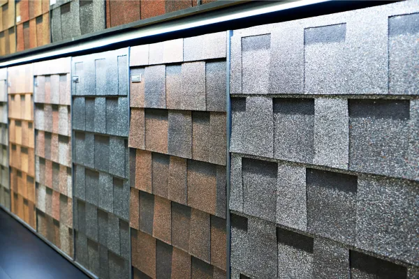 Rows of shingle samples in gray, brown, and tan, displayed on a wall
