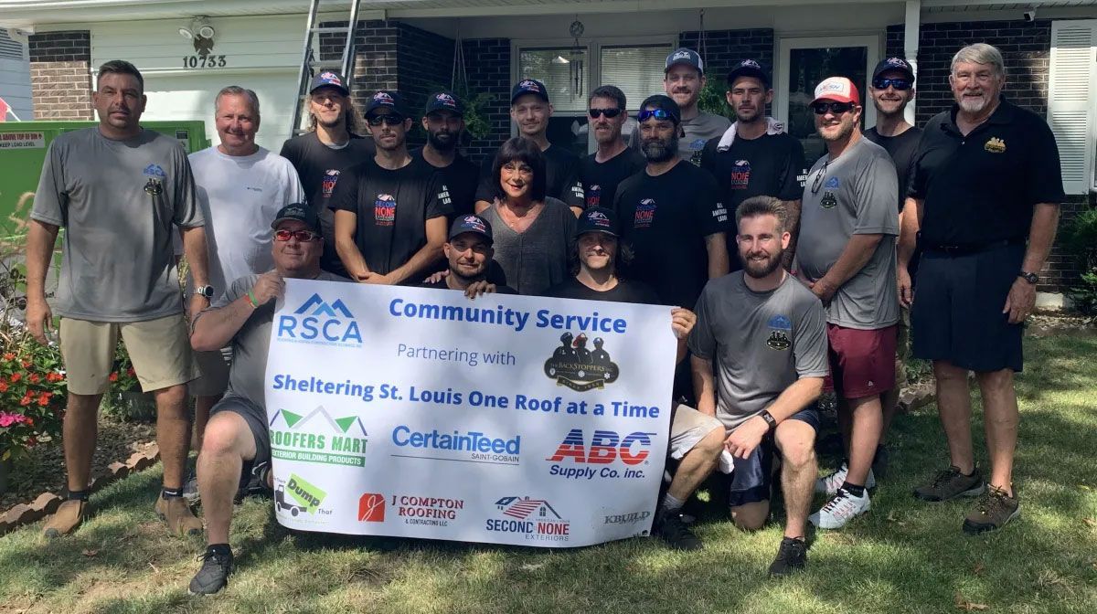 Group of people posing outdoors with a &ldquo;Community Service&rdquo; banner in front of a building.