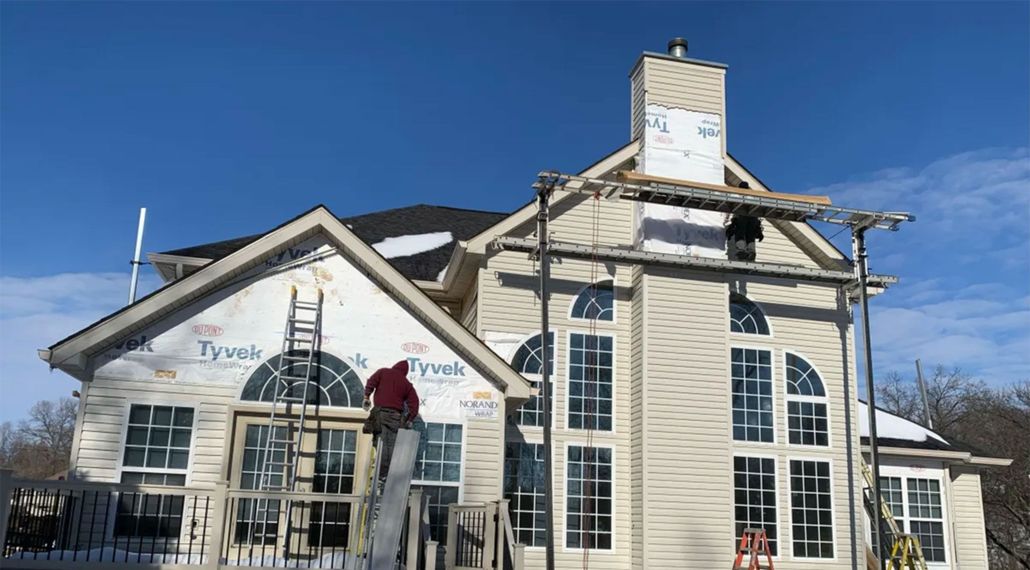 Two-story building with arched windows and damaged roof, under repair on a sunny day
