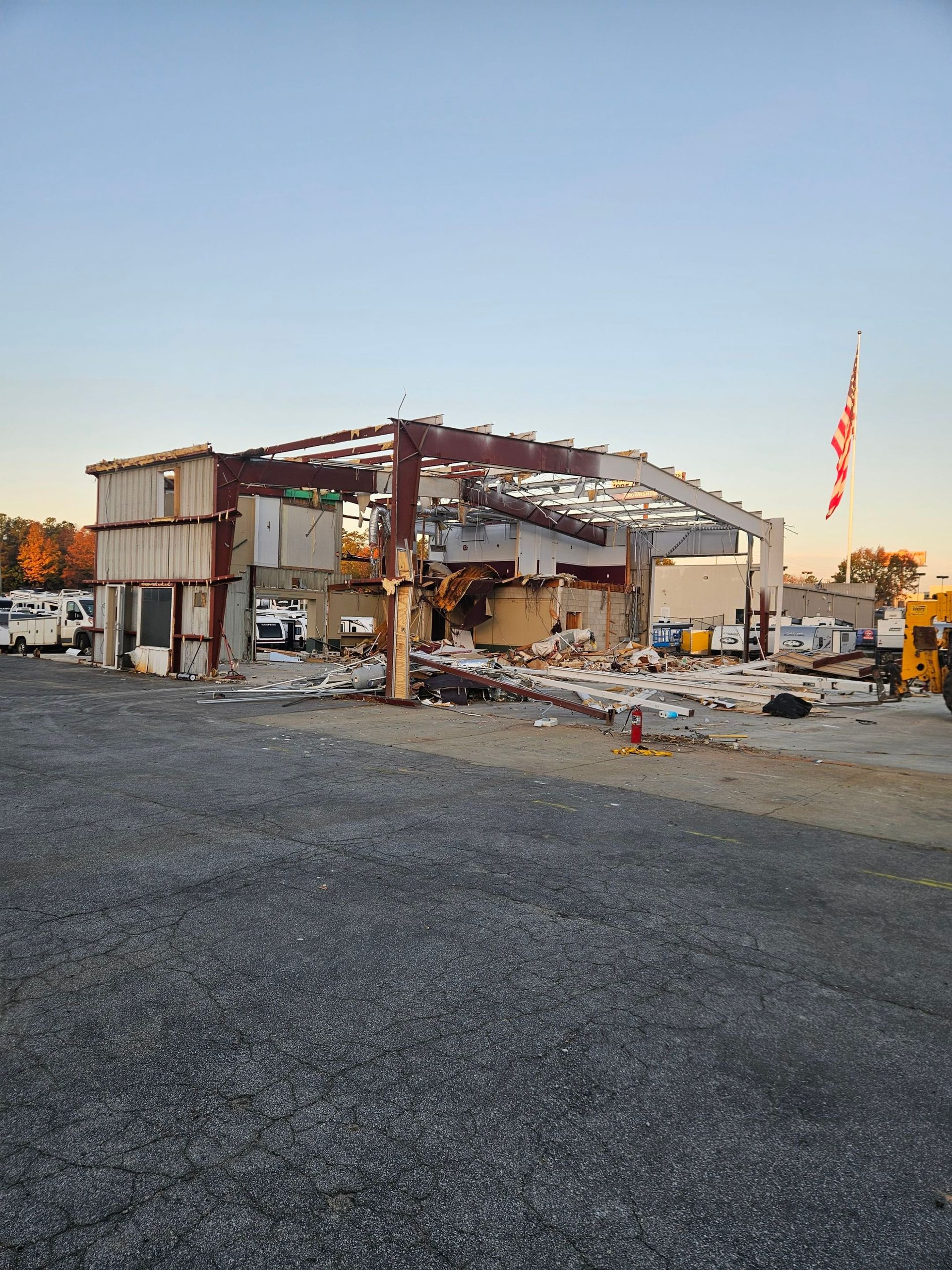 Partially collapsed building with debris and an American flag at sunset