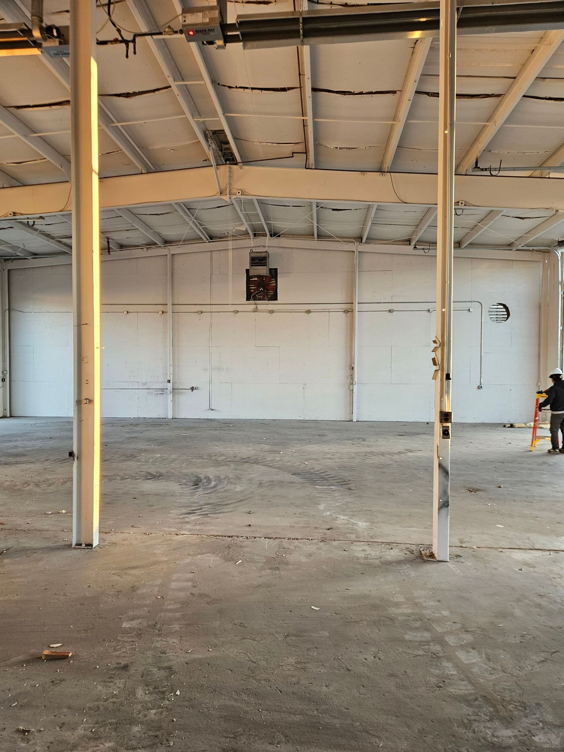 Empty industrial warehouse interior with exposed ceiling, concrete floor, and a few support columns