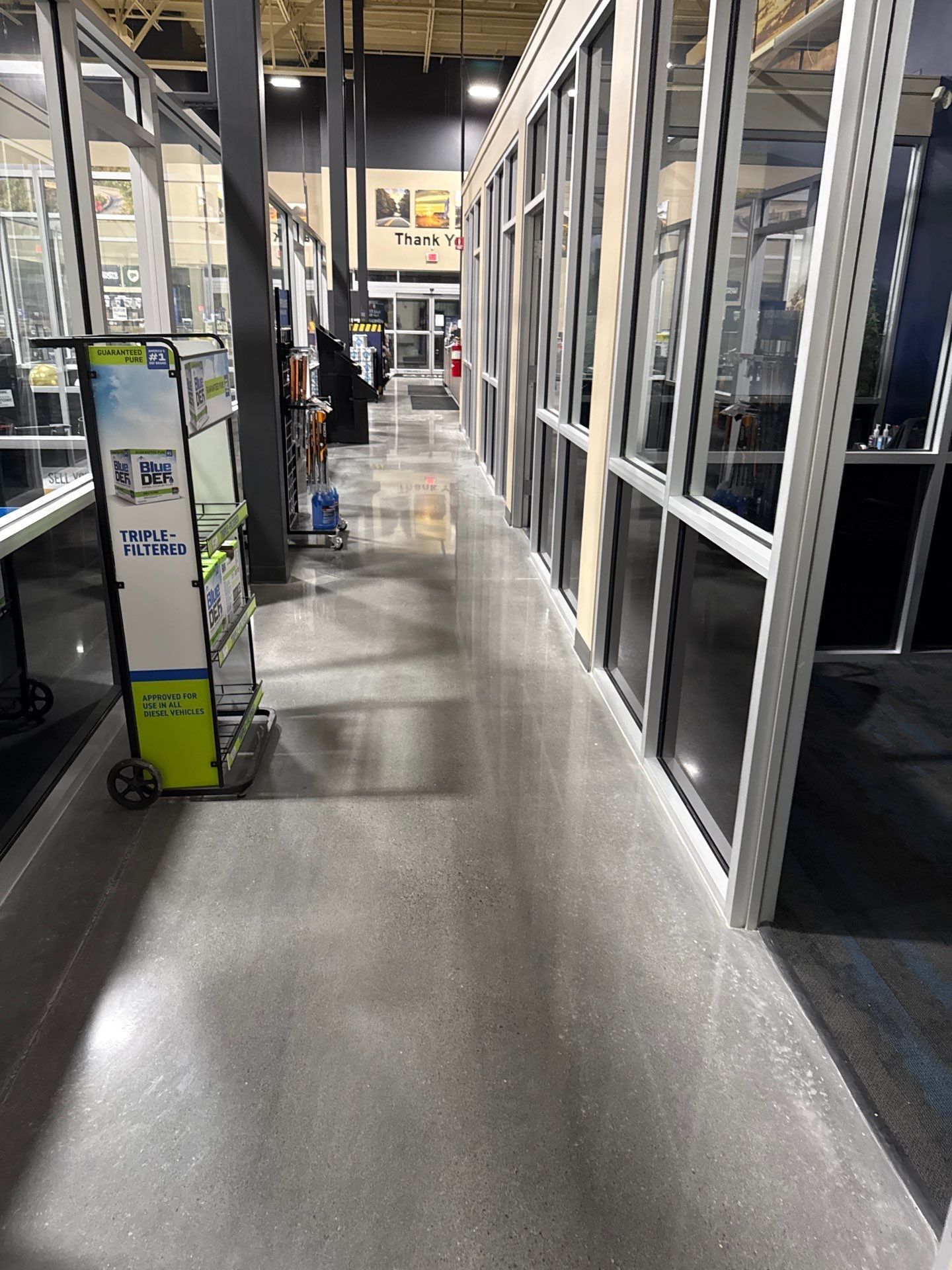 A store aisle with polished floor, glass display cases, and shelves under bright overhead lights.