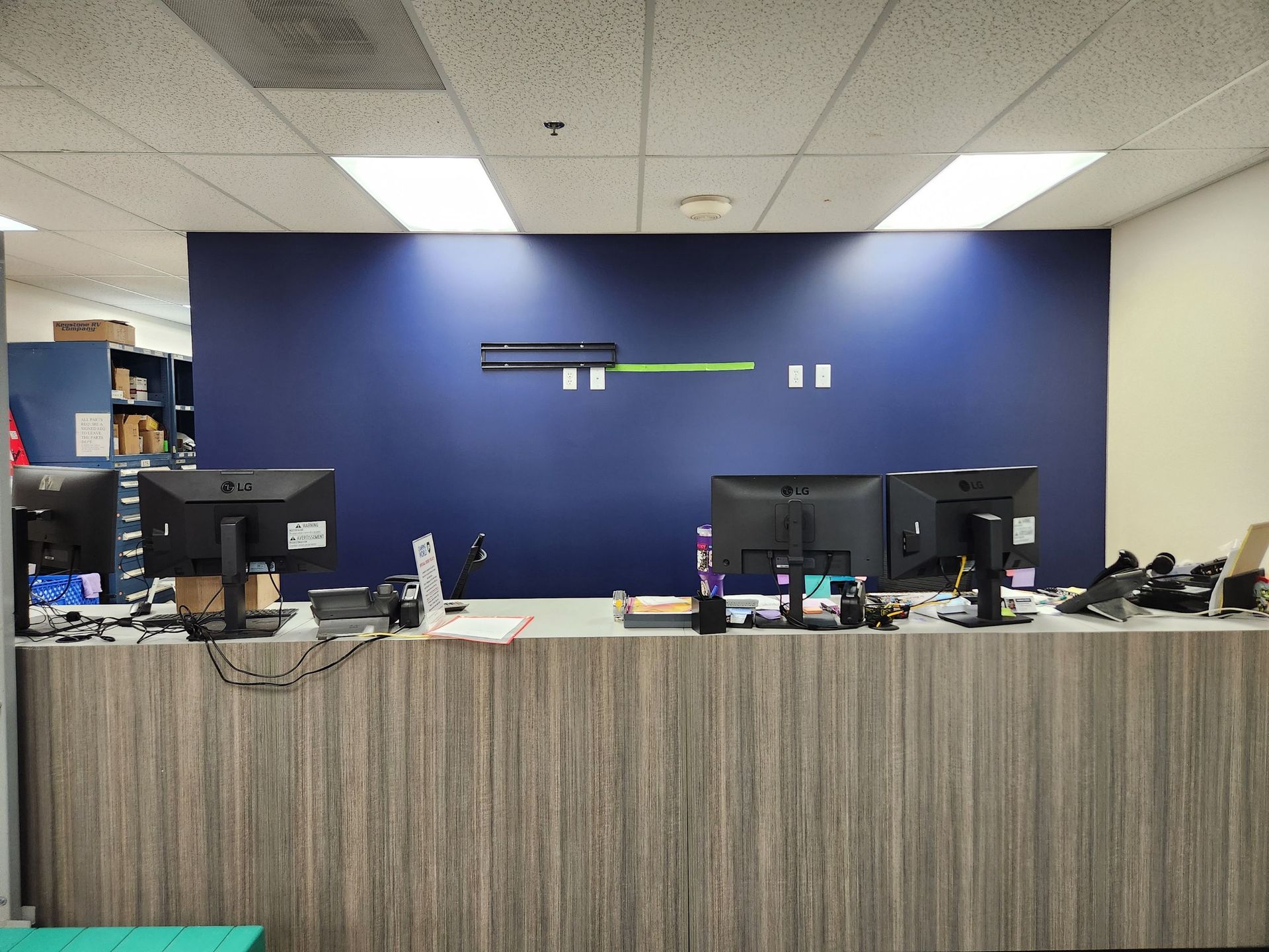 Office reception desk with computer monitors against a blue wall and striped front panel.