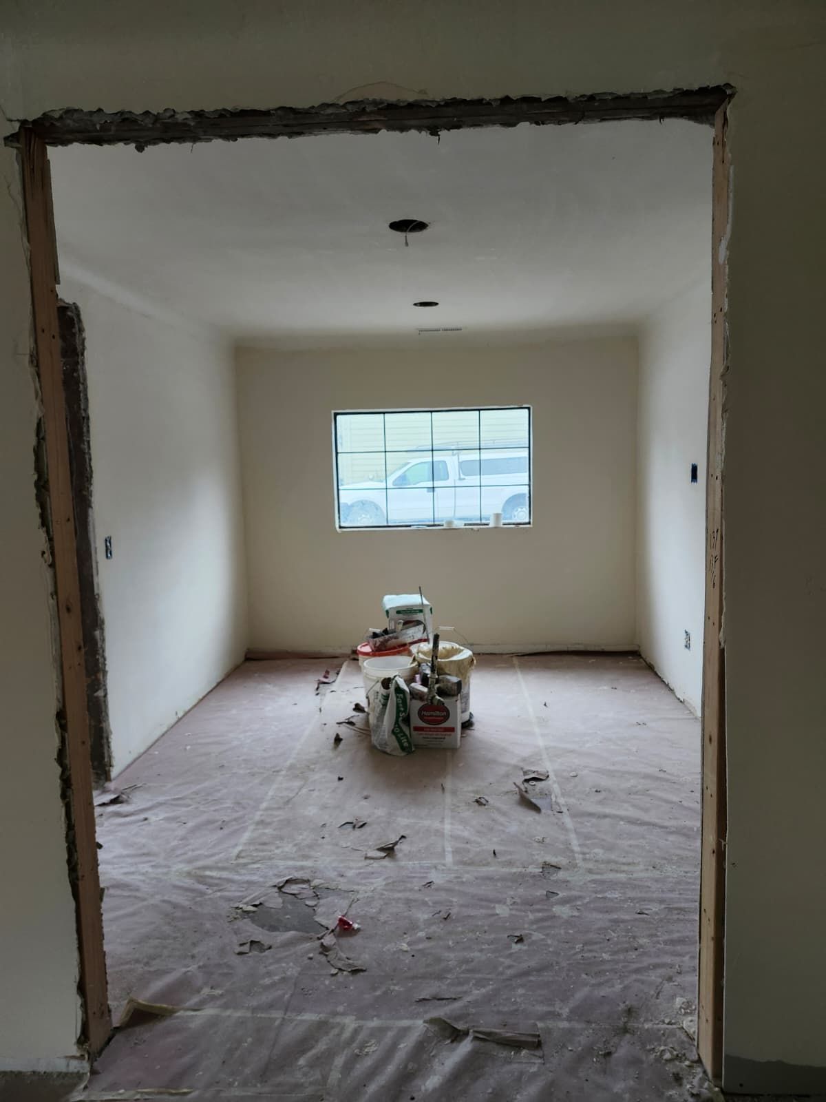 Renovation room with unfinished walls, dusty floor, and tools centered under a window