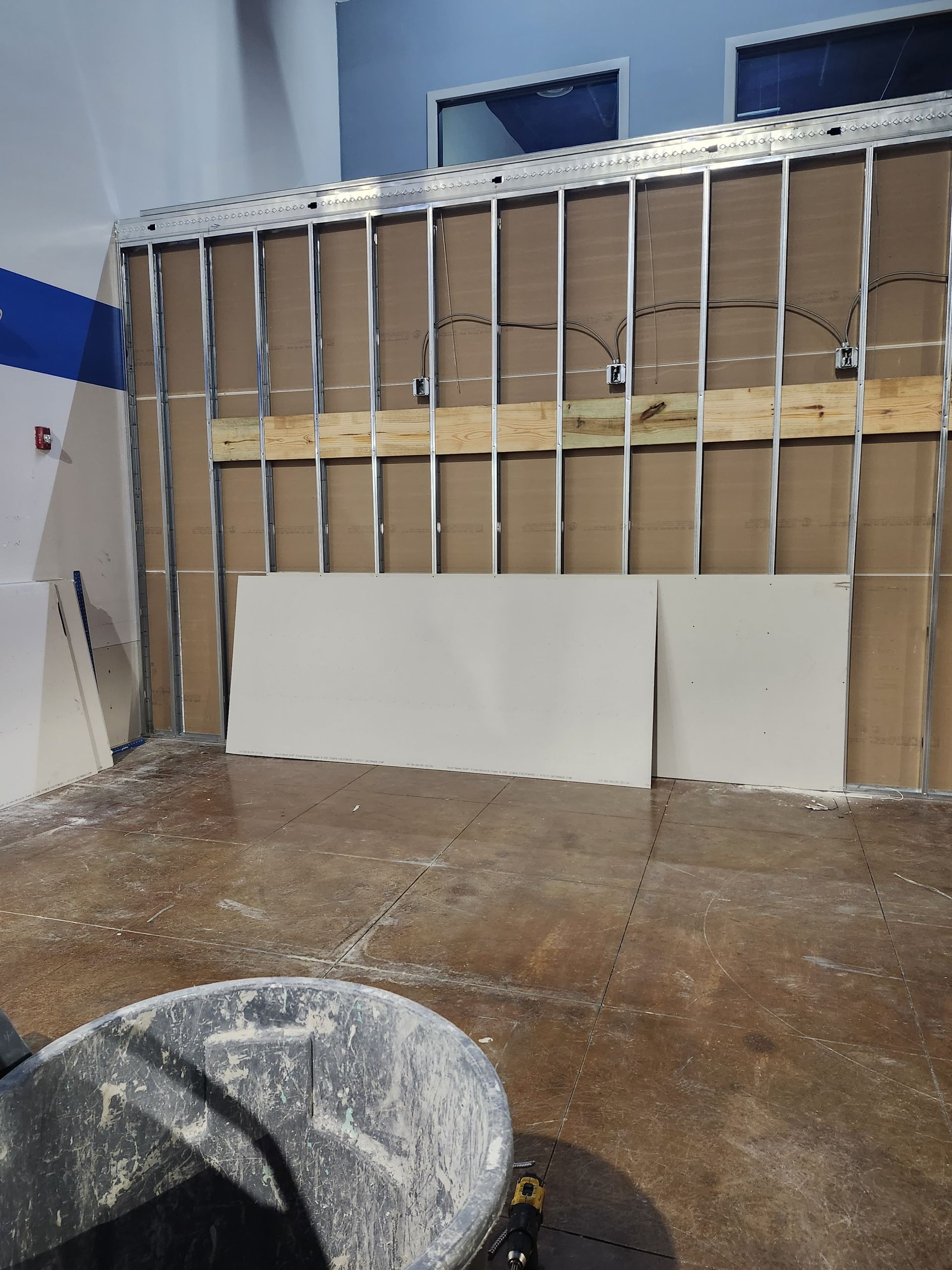 Partially demolished interior wall with exposed studs and debris on the floor