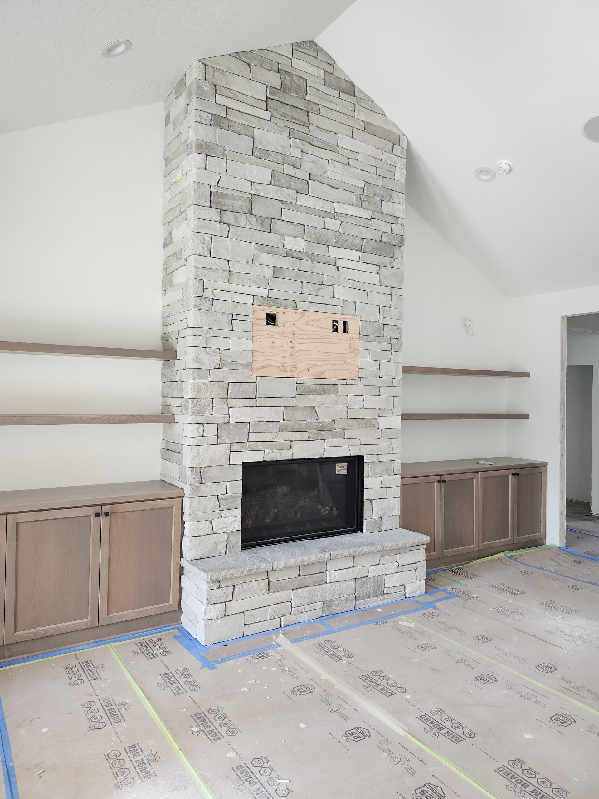 Built-in stone fireplace with cabinets and shelves in a bright living room