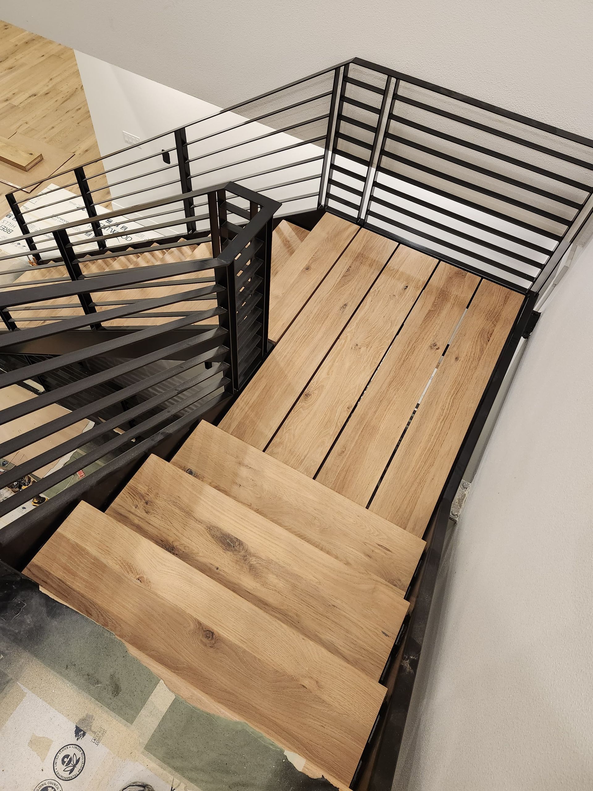 Wooden staircase with black metal railings and light wood flooring in a modern interior.