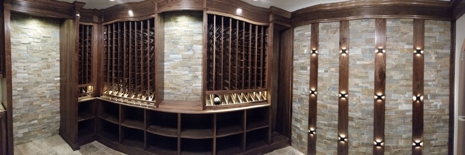 Wood-paneled wine cellar with arched shelves and a central stone wall