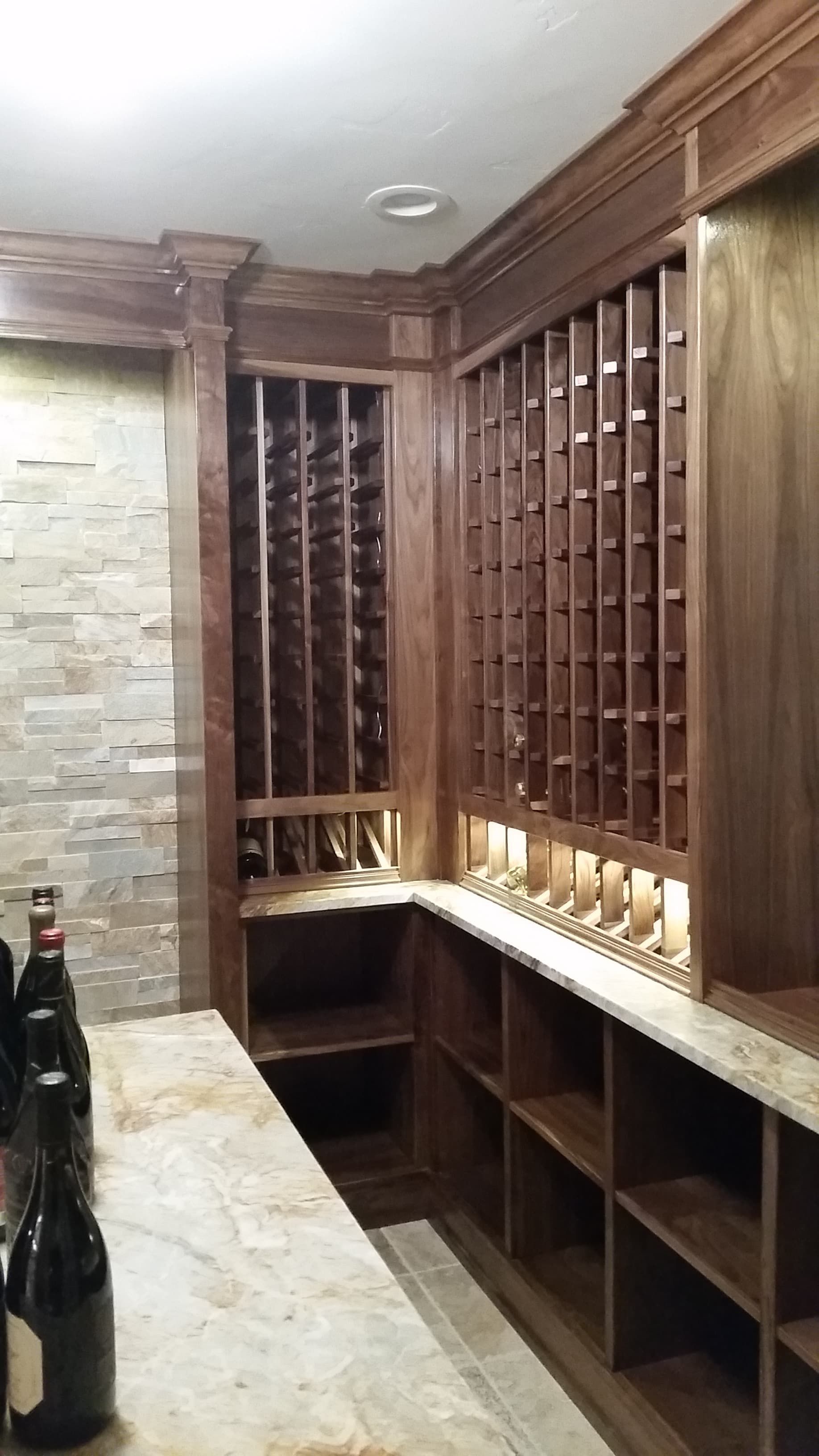 Wooden wine rack and countertop in a cozy home wine cellar with bottles on display