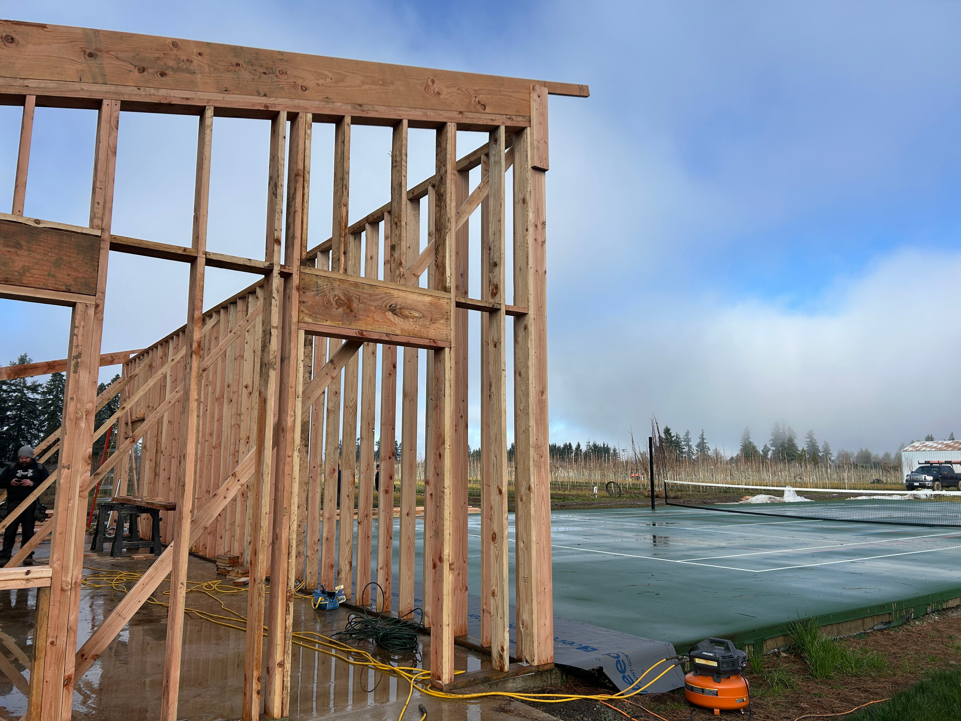 Wood-framed building under construction beside frozen water on a snowy shoreline