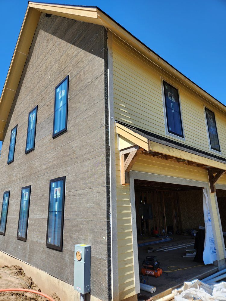 New gray house exterior with blue-trimmed windows and an open garage under construction