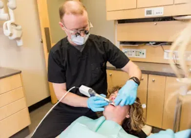 Dentist examining patient's teeth with dental tools in an office.