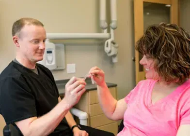 Dentist showing a patient teeth aligner in an office. Both smiling.