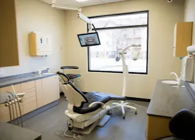 Dental exam room with chair, equipment, and window.