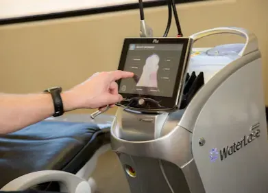 Person using touchscreen on a Waterlase laser machine, indoors.