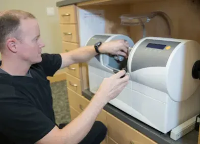 Man working with dental equipment in a clinic setting.
