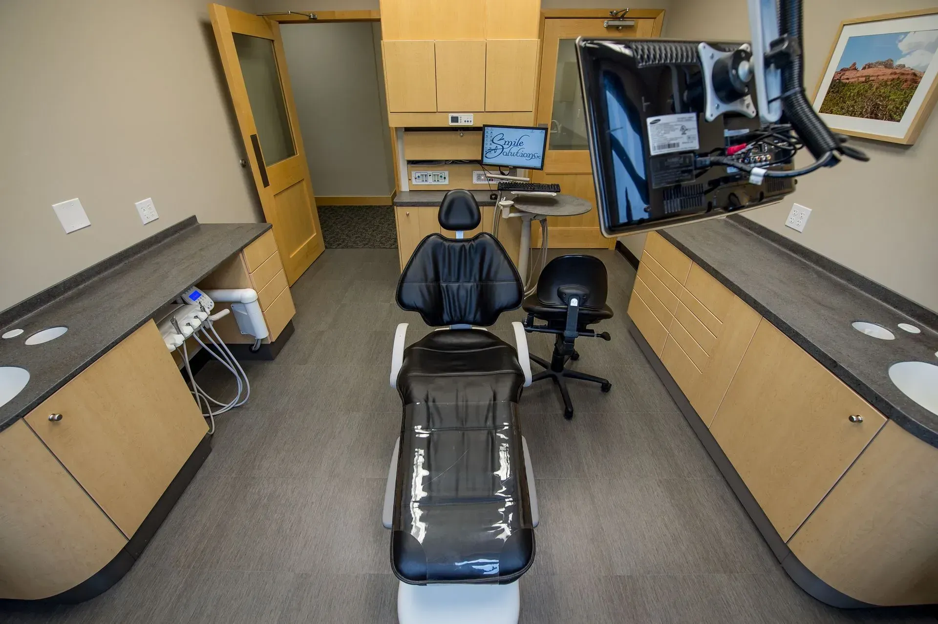 Dental operatory with chair, equipment, cabinets, and two sinks.