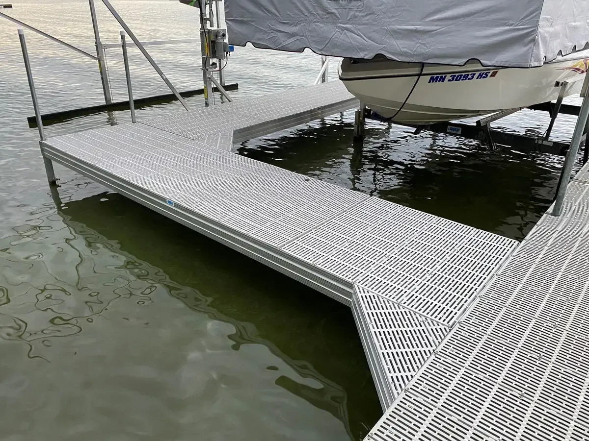 Aluminum dock extends into water, boat in lift under canopy.