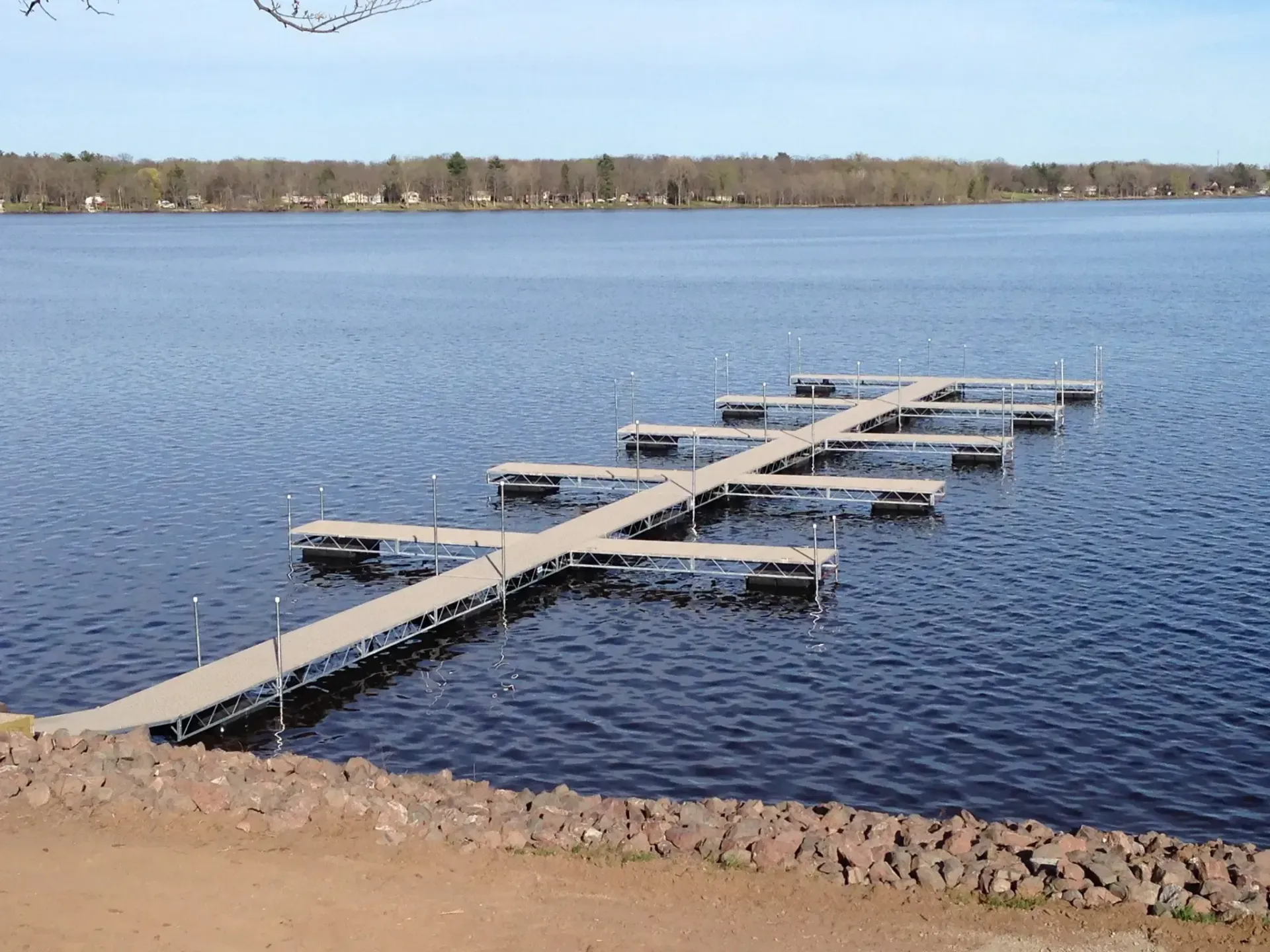 Dock extending into a lake, with several smaller docks branching off. Blue water, clear sky.
