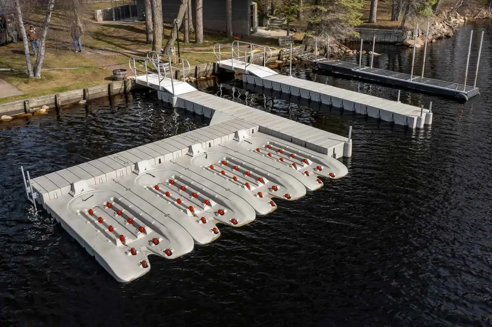 Floating docks on water, gray with red benches, extending into a lake.