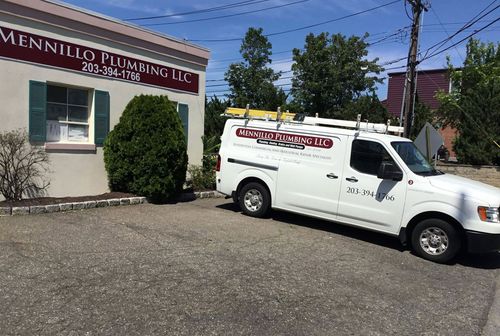 White service van parked outside Mennillo Plumbing Co. building on a sunny day