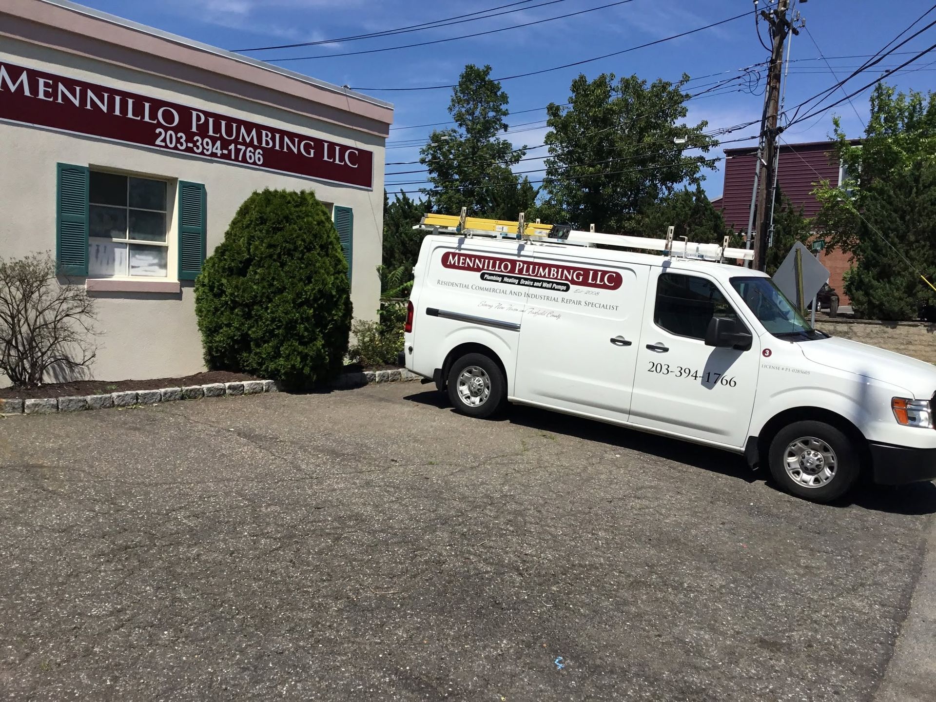 White service van parked outside a small building with a red sign on a sunny day.