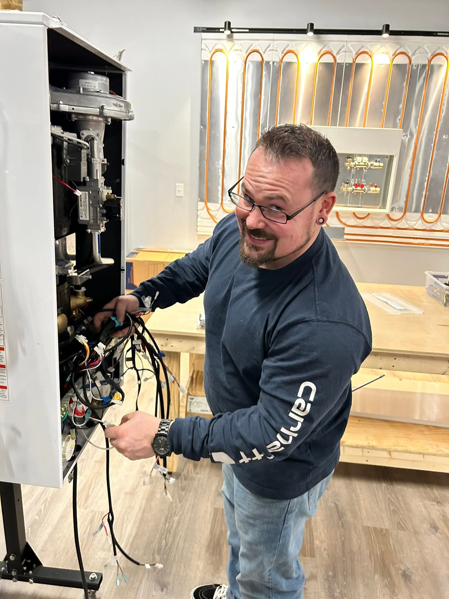 Technician repairing wiring inside an open electrical cabinet in a workshop