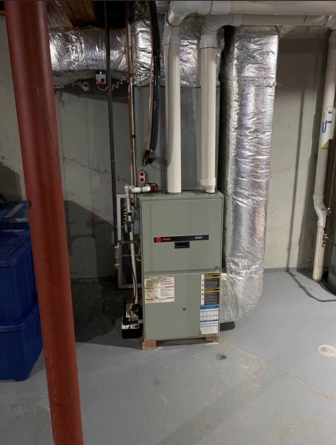 Basement HVAC furnace and ductwork in a utility room with concrete floor.