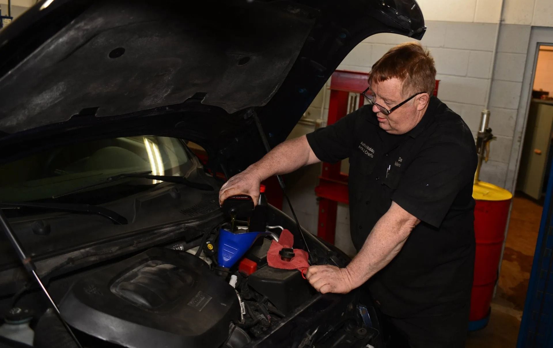 A man is working under the hood of a car.