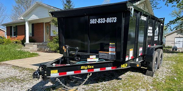A dumpster trailer is parked in front of a house.