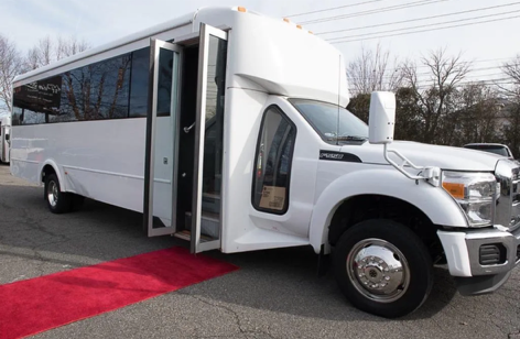 White party bus with open doors and a red carpet.