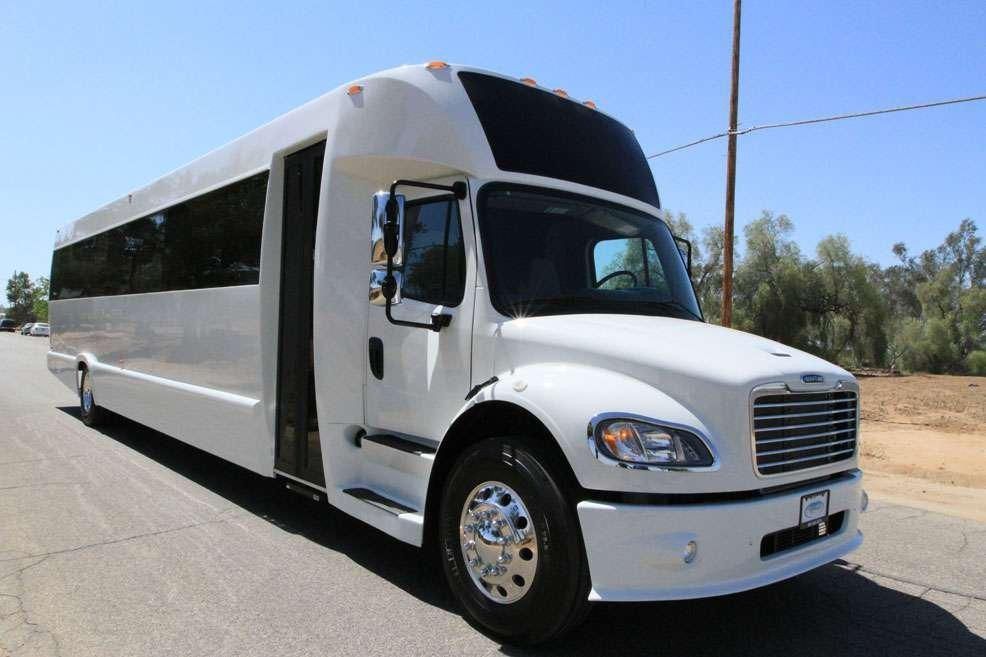 White passenger bus on a paved road, daytime.