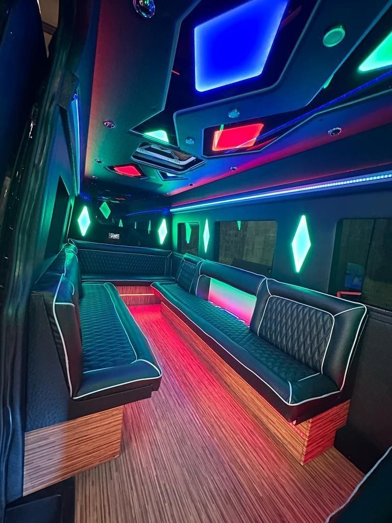 Interior of a party bus with leather seating, neon lights, and diamond-shaped accents.