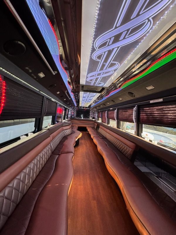 Interior of a luxurious limousine with burgundy leather seating, wood floor, and decorative ceiling lights.