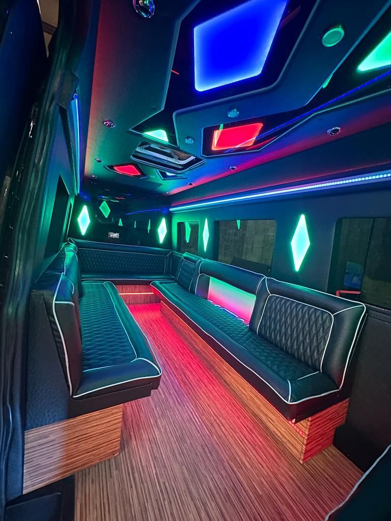 Inside a party bus with neon lights and black leather seating.