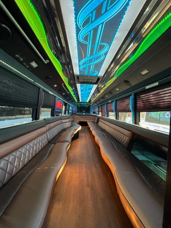Interior of a luxury bus with diamond-stitched brown seating, ambient lighting, and window shades.