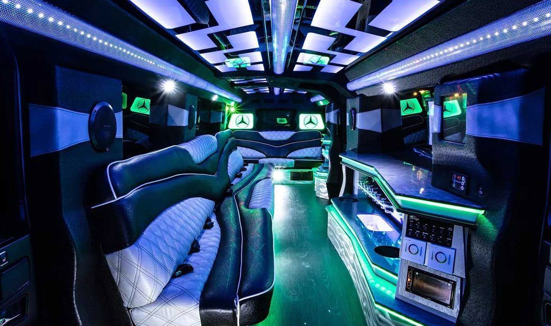 Interior of a limo, lit with blue and green lights. Seats and bar area are visible.