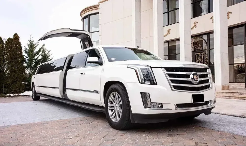 White limousine parked in front of a modern building with open door.