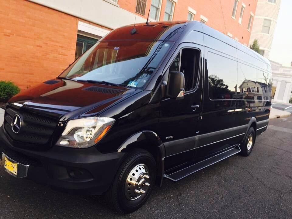 Black Mercedes Sprinter van parked in front of a brick building.